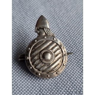 Liten halsnål med viking bak et skjold, antatt i sølv