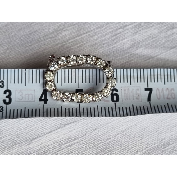 Liten oval nål med strass steiner rundt hele