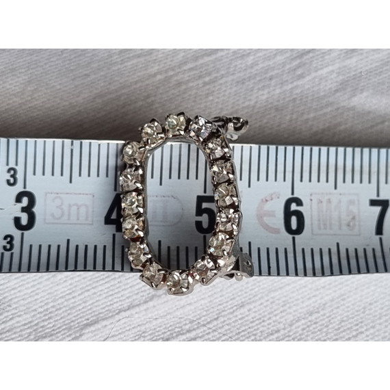 Liten oval nål med strass steiner rundt hele