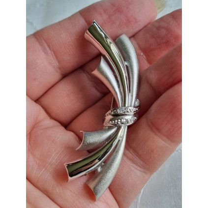 Sølvfarget nål i børstet og glatt metall, ser ut som hvitt gull med to steiner