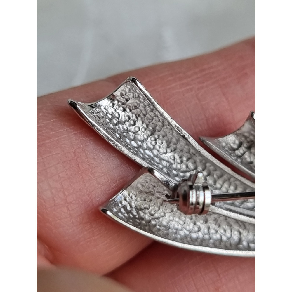 Sølvfarget nål i børstet og glatt metall, ser ut som hvitt gull med to steiner