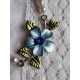 Sjarmerende halssmykke med imiterte perler og med blå blomst dekor i midten, halsgropsmykke